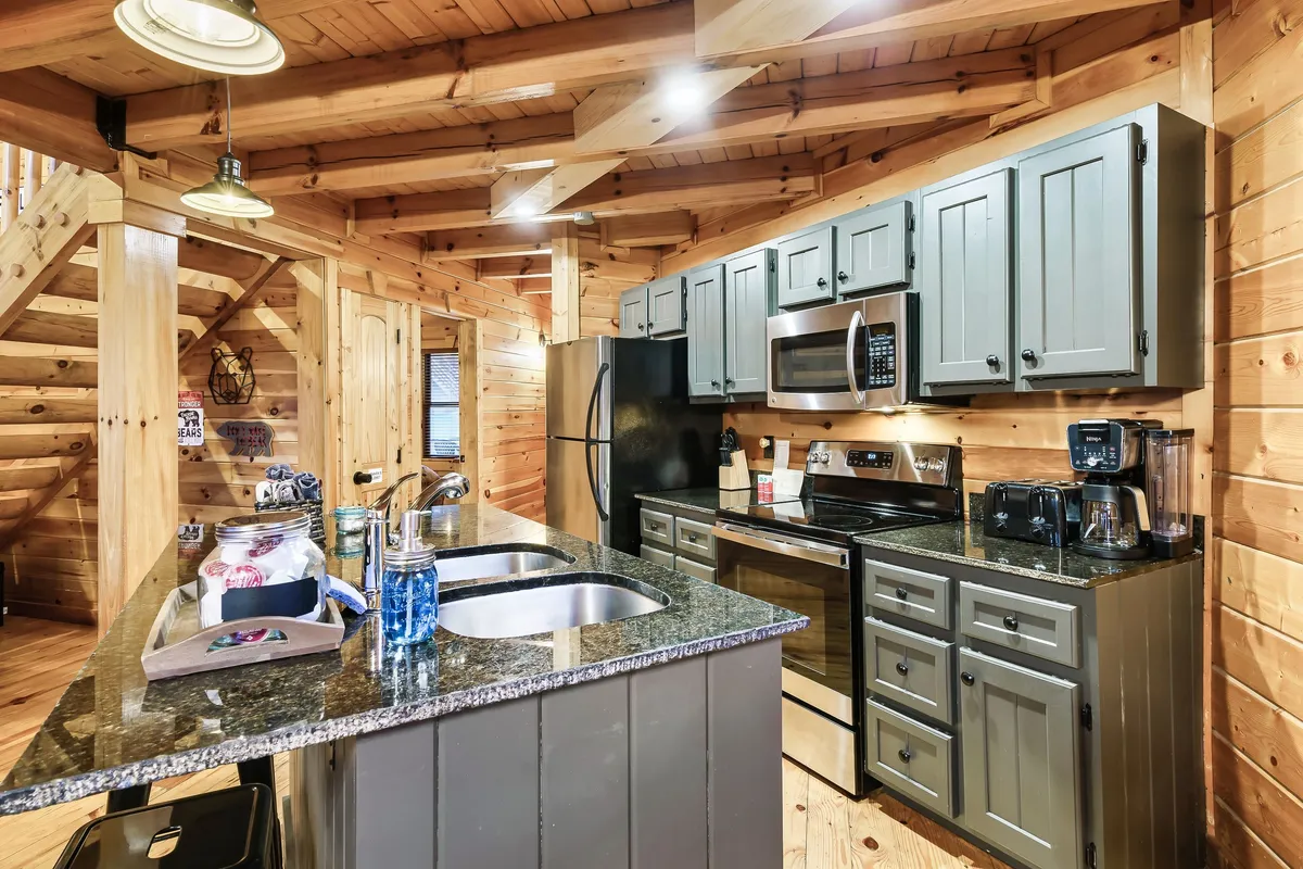 A spacious, open kitchen with granite countertops, stainless steel appliances, wooden cabinetry, and a striking open staircase. The layout is designed for cooking, entertaining, and hosting family gatherings, seamlessly connecting with other living spaces.
