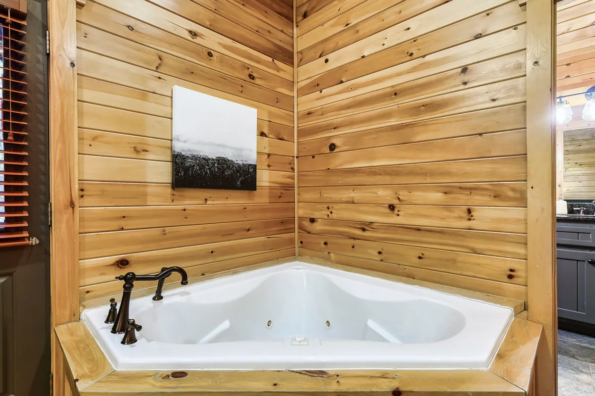 A serene interior bathroom featuring a jacuzzi tub set against wooden walls, accented with tasteful artwork. The atmosphere is calming and spa-like, perfect for luxuriating after outdoor adventures.