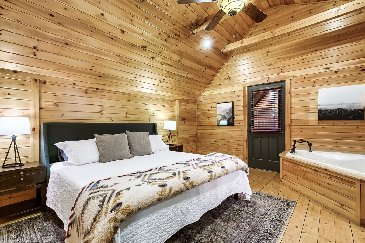 A serene bedroom setting with a comfortable bed and a spacious bathtub, accented by calming artwork and soft lighting. The space exudes a tranquil, spa-like ambiance perfectly suited for unwinding after a day of adventure.